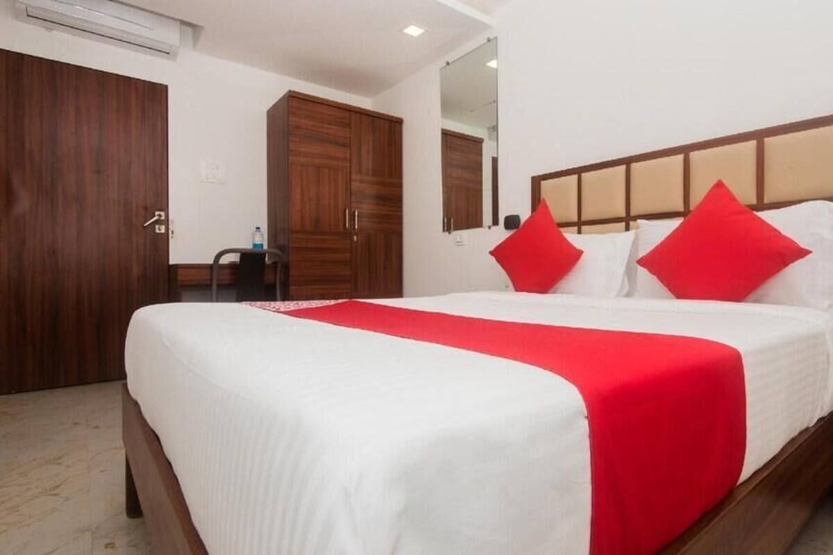 Habitación de hotel con una cama grande, un armario de madera y un espejo.
