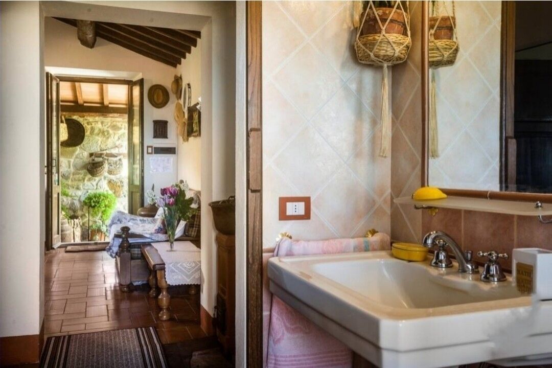 Un baño con un lavamanos grande, un espejo y una cesta colgante.