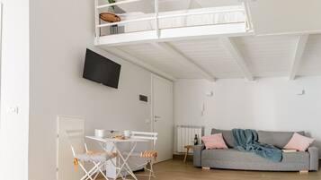A modern apartment with a loft bedroom, a dining area, and a living room.