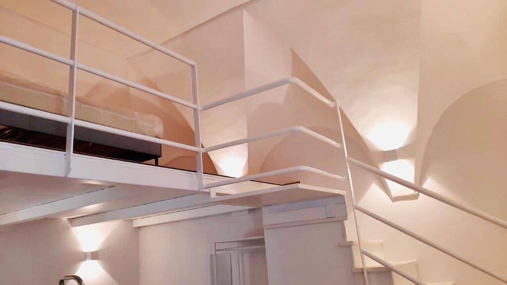 A modern interior with a white staircase and a loft area.