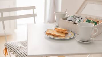 A breakfast setup with toast on a plate, a cup, and a box of tea on a white table.