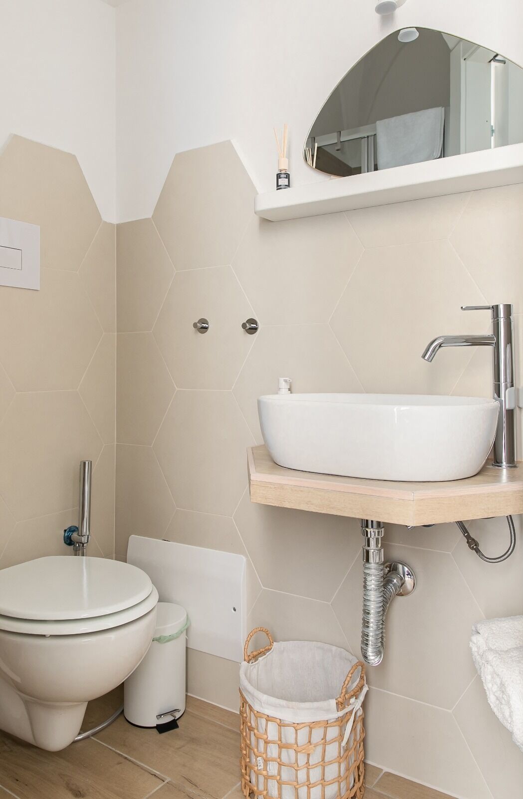 Un baño con inodoro y lavamanos blancos, y un espejo sobre el lavamanos.