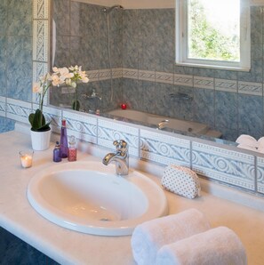 Bathroom features a large sink, bathtub, and a window above the tub.