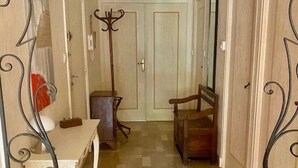A narrow hallway with a wooden floor, a white door at the end, and a coat rack with a mirror. - Bright F2 Apartment with Terrace, Parking, and WiFi in Amélie-les-Bains (Amélie-les-Bains-Palalda)