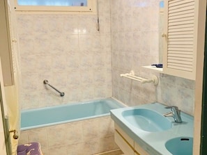 A bathroom with a bathtub, a sink, and a towel rack.