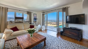 A spacious living room with a large window, a flat-screen TV, a wooden coffee table, and a sofa with red cushions. - Fabulous 5 Bedroom Villa near Cannes perfect for the Lions Festival. 
 (Théoule-sur-Mer)