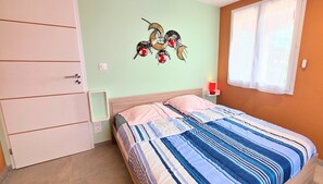 Une chambre à coucher avec un lit, une table de chevet, un élément décoratif mural et une fenêtre.