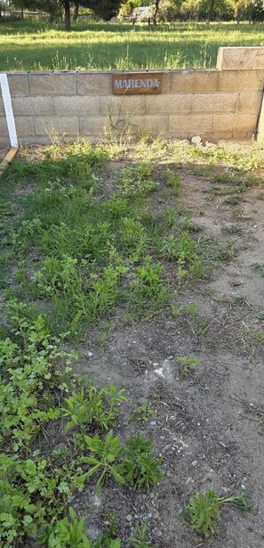 Un espacio cubierto de hierba con un letrero que dice 'MARENDA' en una pared de piedra.