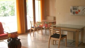 A dining area with a glass table, wooden chairs, and a vase of flowers.