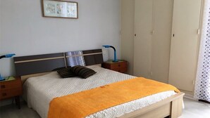 A bedroom with a bed, nightstands, a wardrobe, and a framed picture on the wall.
