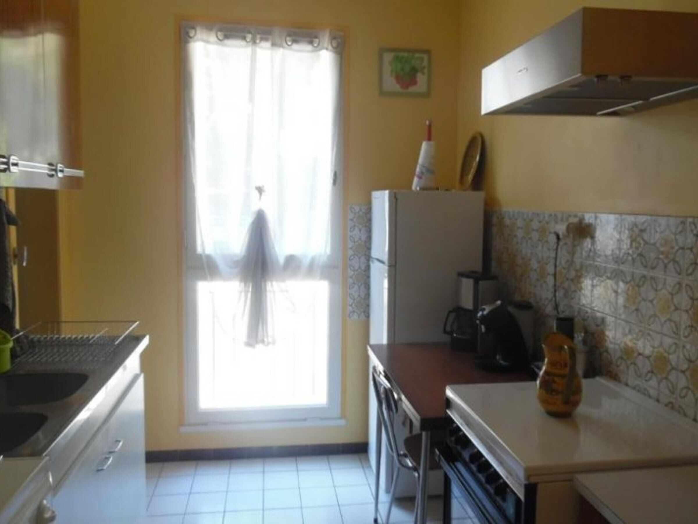 Una cucina con finestra, frigorifero, forno a microonde e lavandino.