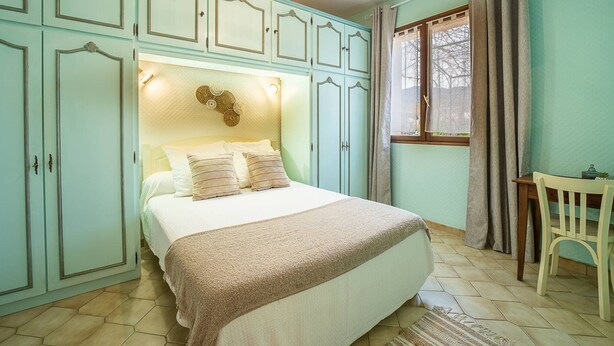 Ein Schlafzimmer mit einem Bett, einem Schreibtisch und einem Sessel.