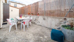 Eine Terrasse im Freien mit Tisch und Stühlen, einem Bambuszaun und einer Betonwand mit Steinen.