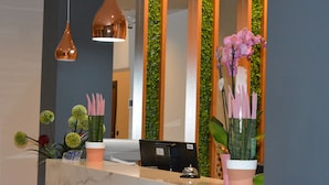 Ein Empfangsschalter mit einem Computer, einem Telefon und einer Vase mit rosafarbenen Orchideen.