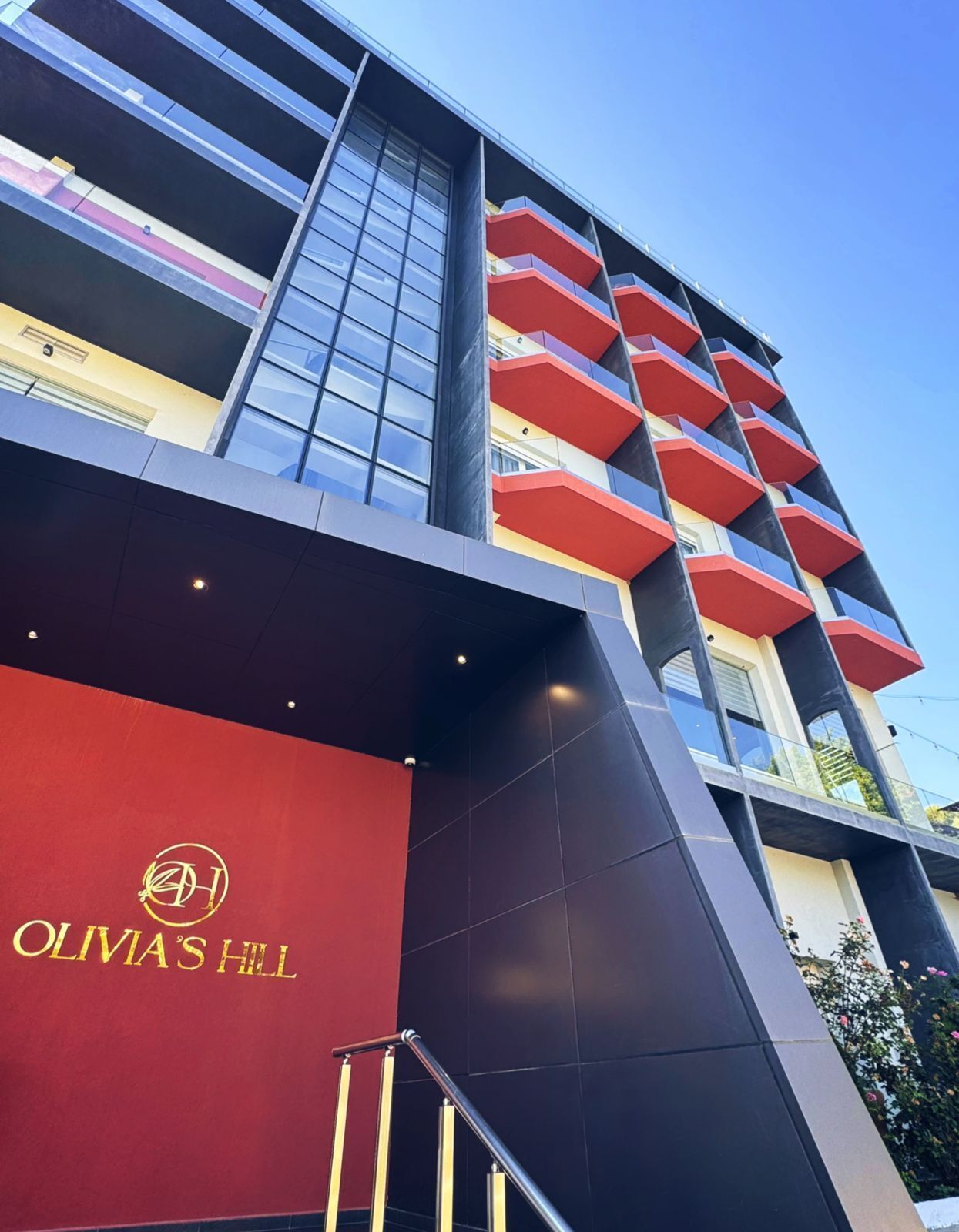 Un bâtiment moderne, sur lequel on peut voir une grande enseigne rouge portant l’inscription « OLIVAS’S HILL ».