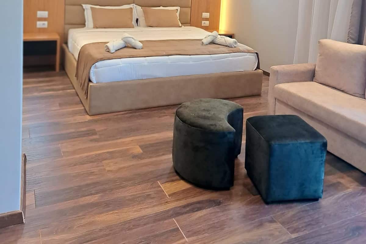 Een moderne slaapkamer met een groot bed, een bank en twee poefs.