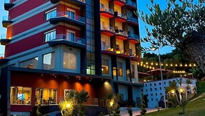 Ein mehrstöckiges Hotel mit Balkonen, einem gut beleuchteten Eingangsbereich und einer gepflegten Gartenanlage.
