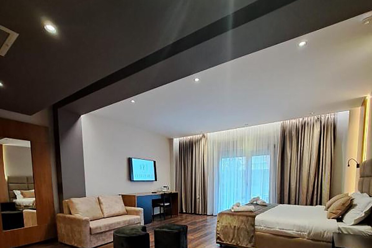 Een ruime woonkamer met een houten vloer, twee banken, een salontafel en een flatscreen televisie aan de muur.