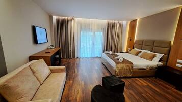 Habitación de hotel con cama, sofá, escritorio y televisor.