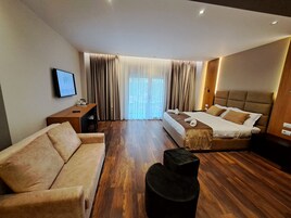 Habitación de hotel con cama, sofá, escritorio y televisor.