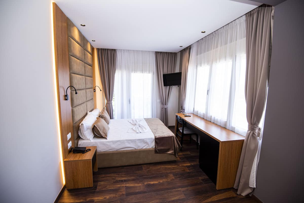 Een moderne hotelkamer met een bed, bureau en televisie.