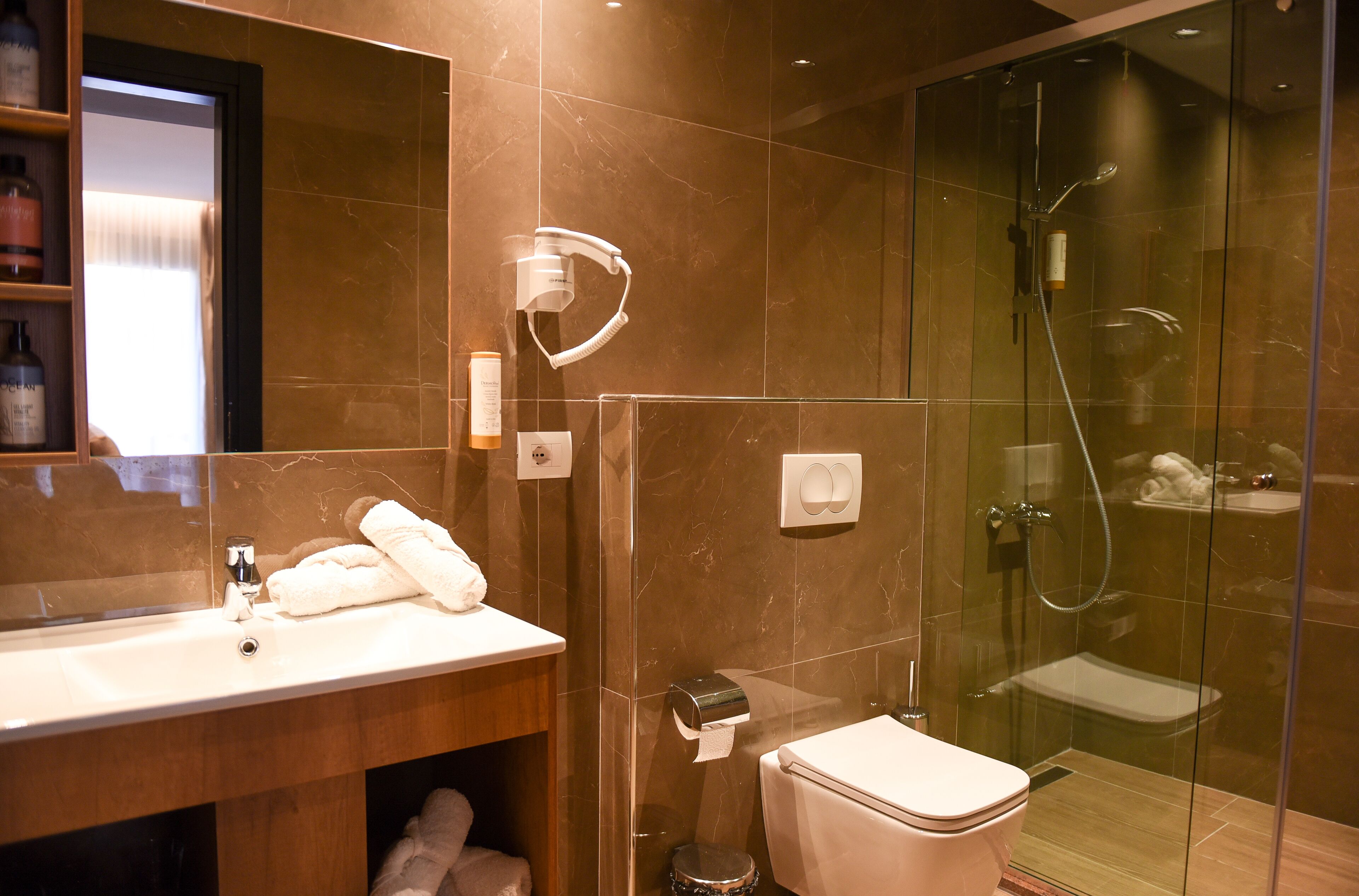 A modern bathroom with a glass-enclosed shower, a white sink, and a toilet.