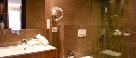A modern bathroom with a glass-enclosed shower, a white sink, and a toilet.