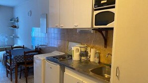 A compact kitchen with white cabinets, a small refrigerator, a coffee maker, and a microwave. - Charming Studio for 2 with Parking, Near Thermal Baths and City Center (Amélie-les-Bains-Palalda)