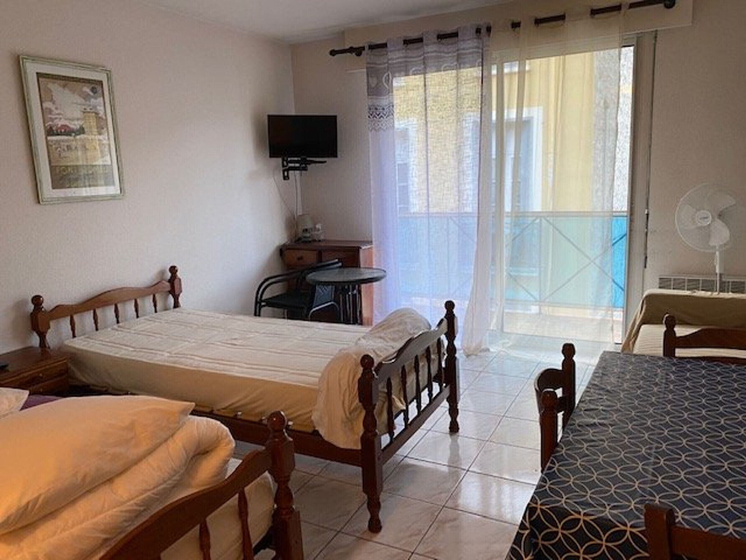 A hotel room with a bed, a small table, a chair, a TV, and a balcony with a view.