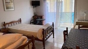 A hotel room with a bed, a small table, a chair, a TV, and a balcony with a view. - Charming Studio for 2 with Parking, Near Thermal Baths and City Center (Amélie-les-Bains-Palalda)