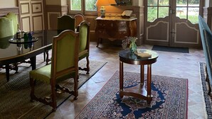 A spacious room with a large dining table, two chairs, a small side table with a lamp, and a large window with a view of greenery. - Charming 18th century house entirely renovated (Pexiora)