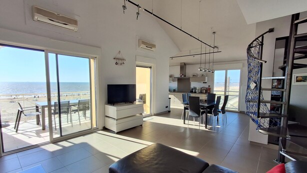 A spacious living area with a large TV, dining table, and a view of the beach. - Châtelaillon-Plage: 4-room apartment, 6 people, terrace, WIFI (Châtelaillon-Plage)