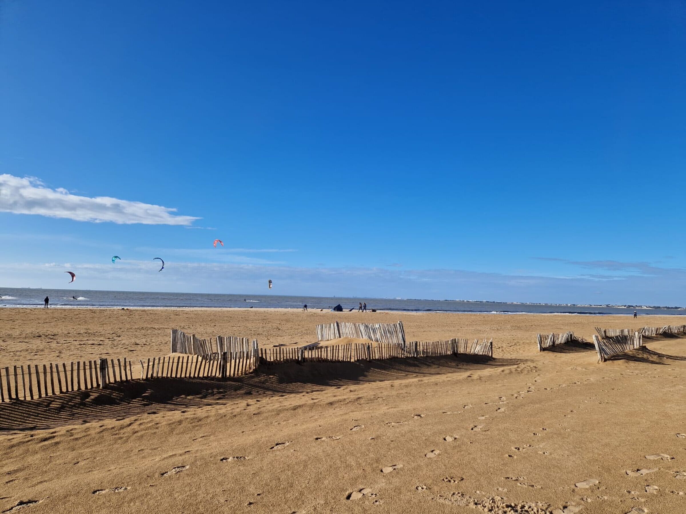 A sandy beach with wooden fences and a clear blue sky.