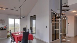 A modern dining area with a red tablecloth, chairs, and a view through a glass door. - Châtelaillon-Plage: 4-room apartment, 6 people, terrace, WIFI (Châtelaillon-Plage)