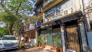 A hotel with a closed entrance, potted plants, and a parked car. - Hotel Signature Inn (Mumbai)