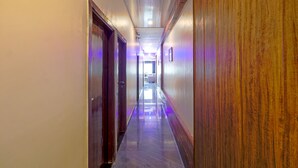 A long, narrow hallway with wooden paneling on the right and a polished floor. - Hotel Signature Inn (Mumbai)