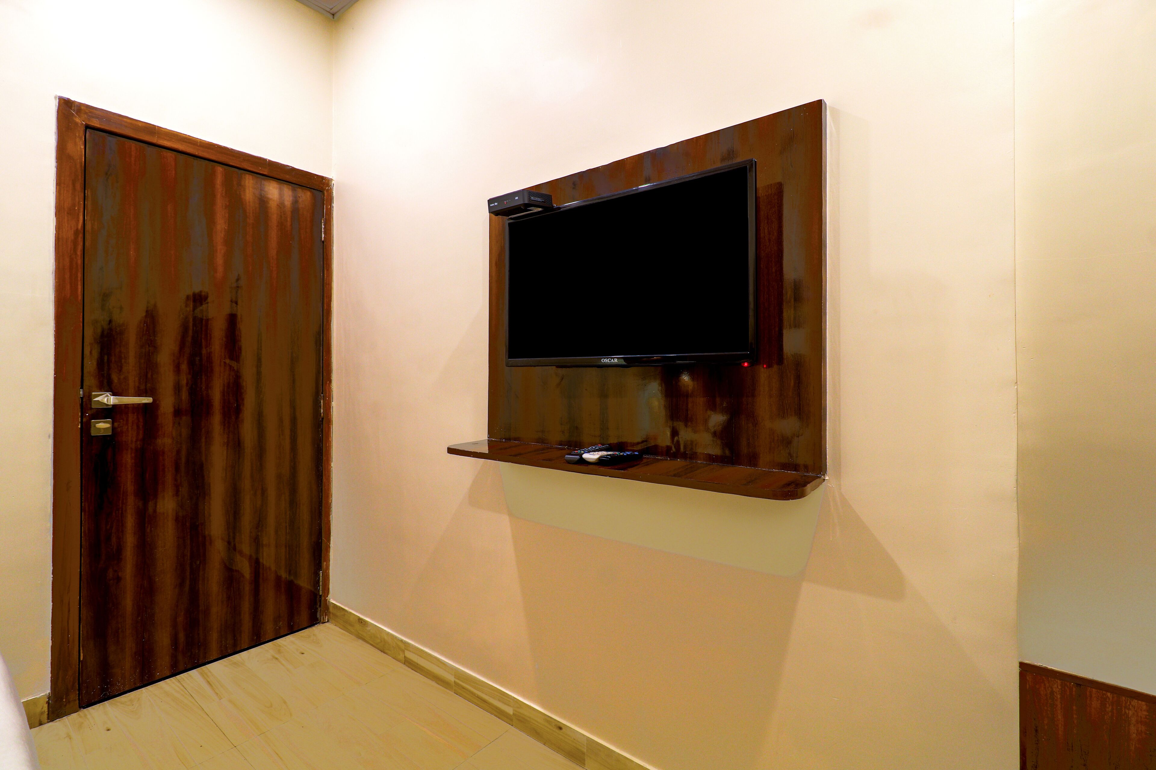 A hallway with a wooden door and a mounted flat-screen TV on the wall.