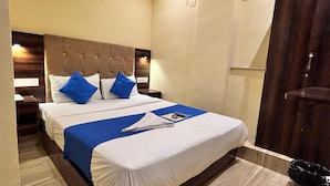 A hotel room with a large bed, two nightstands, a wooden wardrobe, and a tiled floor. - Hotel Signature Inn (Mumbai)