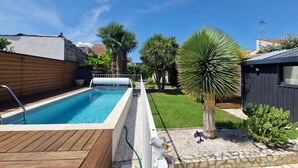 A swimming pool with a wooden deck, surrounded by a garden with various plants and a small shed. - Beachside Villa with Pool - 2BR, 4 Guests, Near Market & Beach (Châtelaillon-Plage)