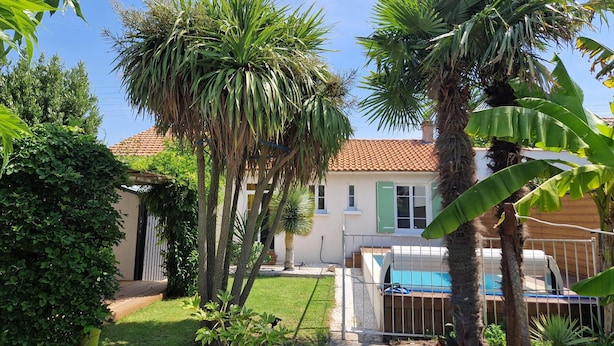 A house with a swimming pool, surrounded by various tropical plants and trees. - Beachside Villa with Pool - 2BR, 4 Guests, Near Market & Beach (Châtelaillon-Plage)