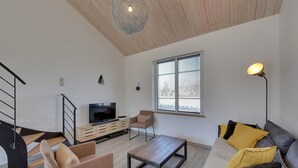 A modern living room with a TV, sofa, coffee table, and a staircase. - Beachside Villa with Pool - 2BR, 4 Guests, Near Market & Beach (Châtelaillon-Plage)