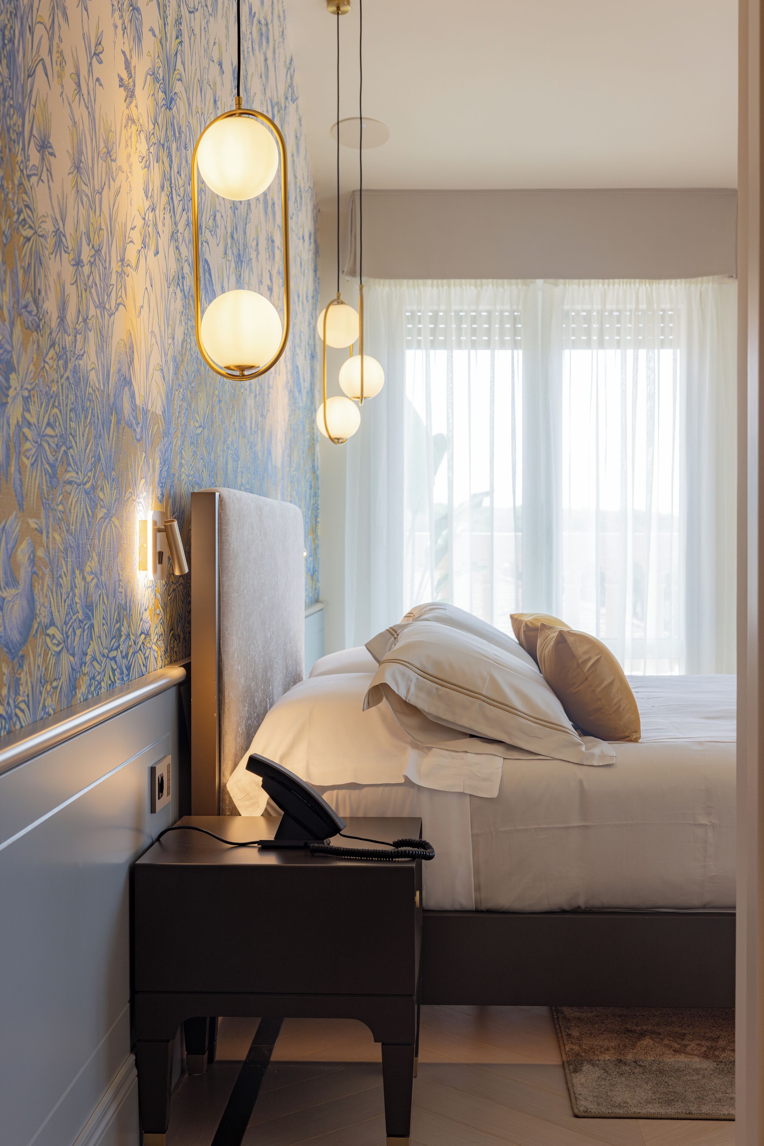 Een hotelkamer met een bed, nachtkastje en telefoon.