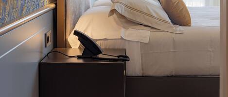 A hotel room with a bed, bedside table, and a telephone.