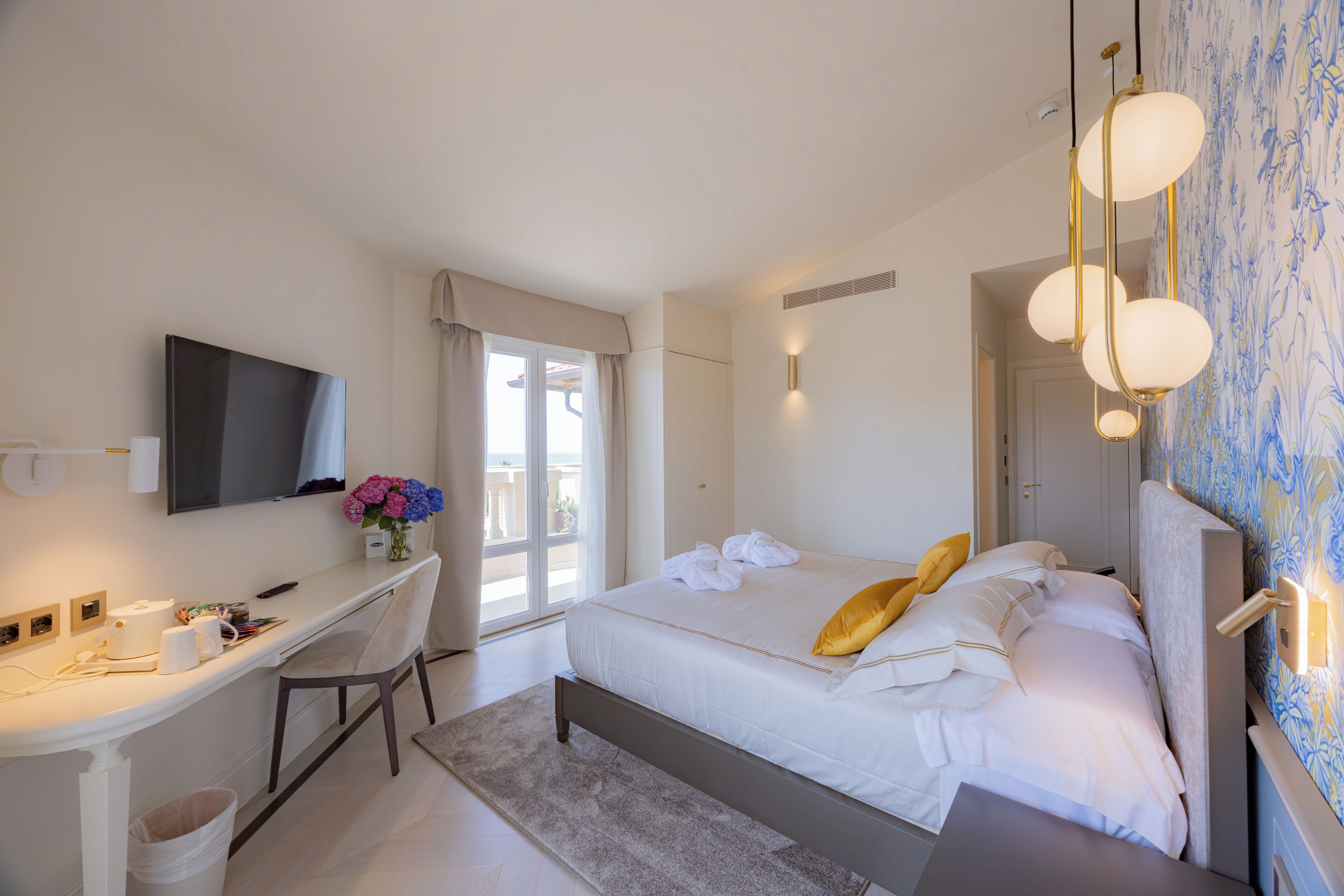 A hotel room with a bed, desk, and a television.