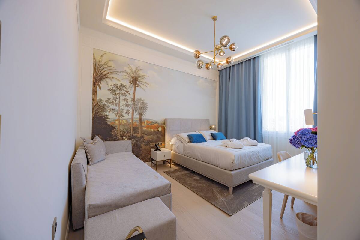 Une chambre d’hôtel moderne, équipée d’un lit, d’un canapé, d’un bureau et d’un tableau au mur.