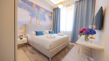 Une chambre d’hôtel moderne avec un grand lit, une table de chevet et un bureau agrémenté d’un vase de fleurs.