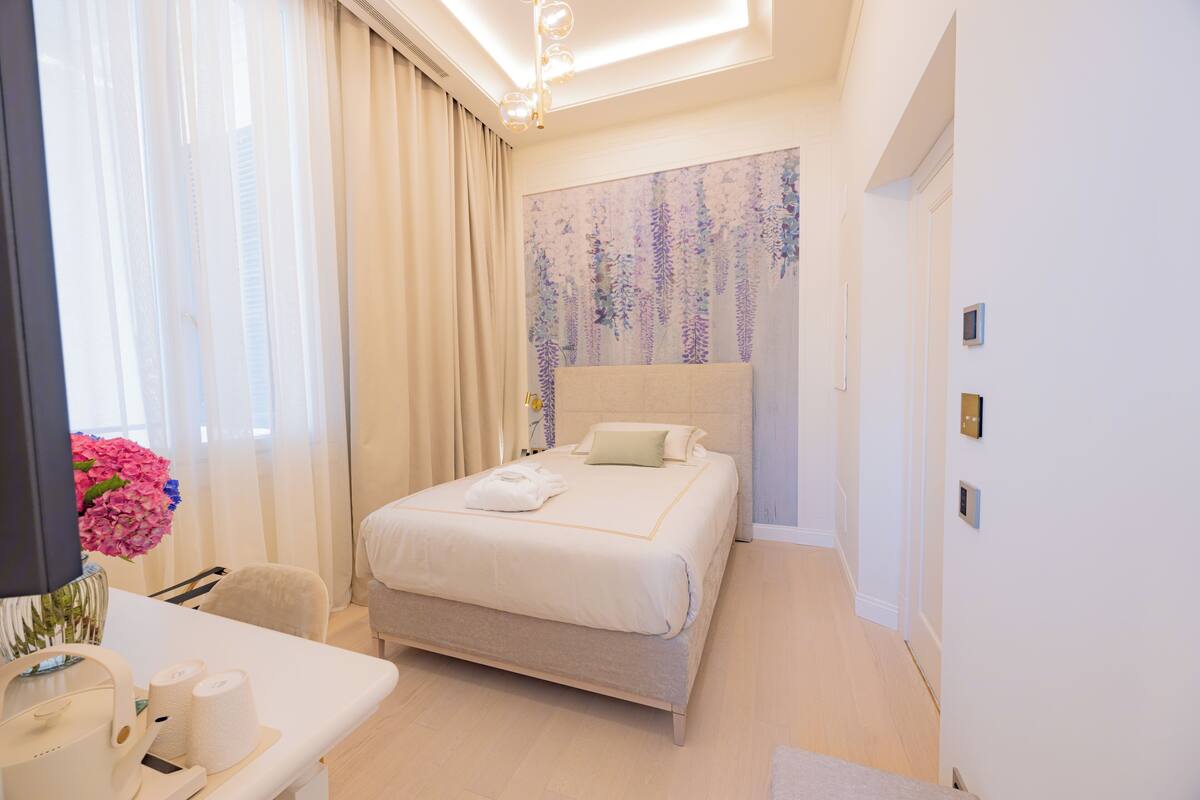 Une chambre d’hôtel moderne avec un grand lit, un bureau avec une chaise et un vase de fleurs.