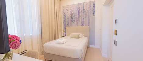 Una habitación de hotel moderna con una cama grande, un escritorio con una silla y un jarrón con flores.