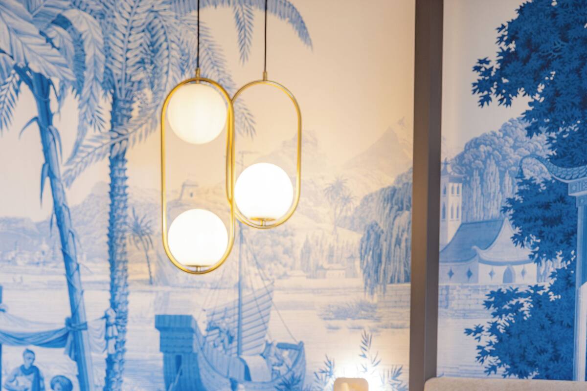 Une chambre d’hôtel avec un lit, une table de chevet, un téléphone, un oreiller jaune et une fresque murale.