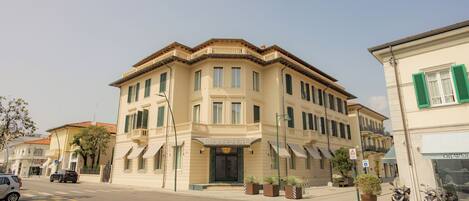 A corner building with a beige facade, multiple windows, and a balcony.